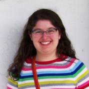 Photograph of Alexandra Lazar, wearing a multicolored striped sweater and smiling